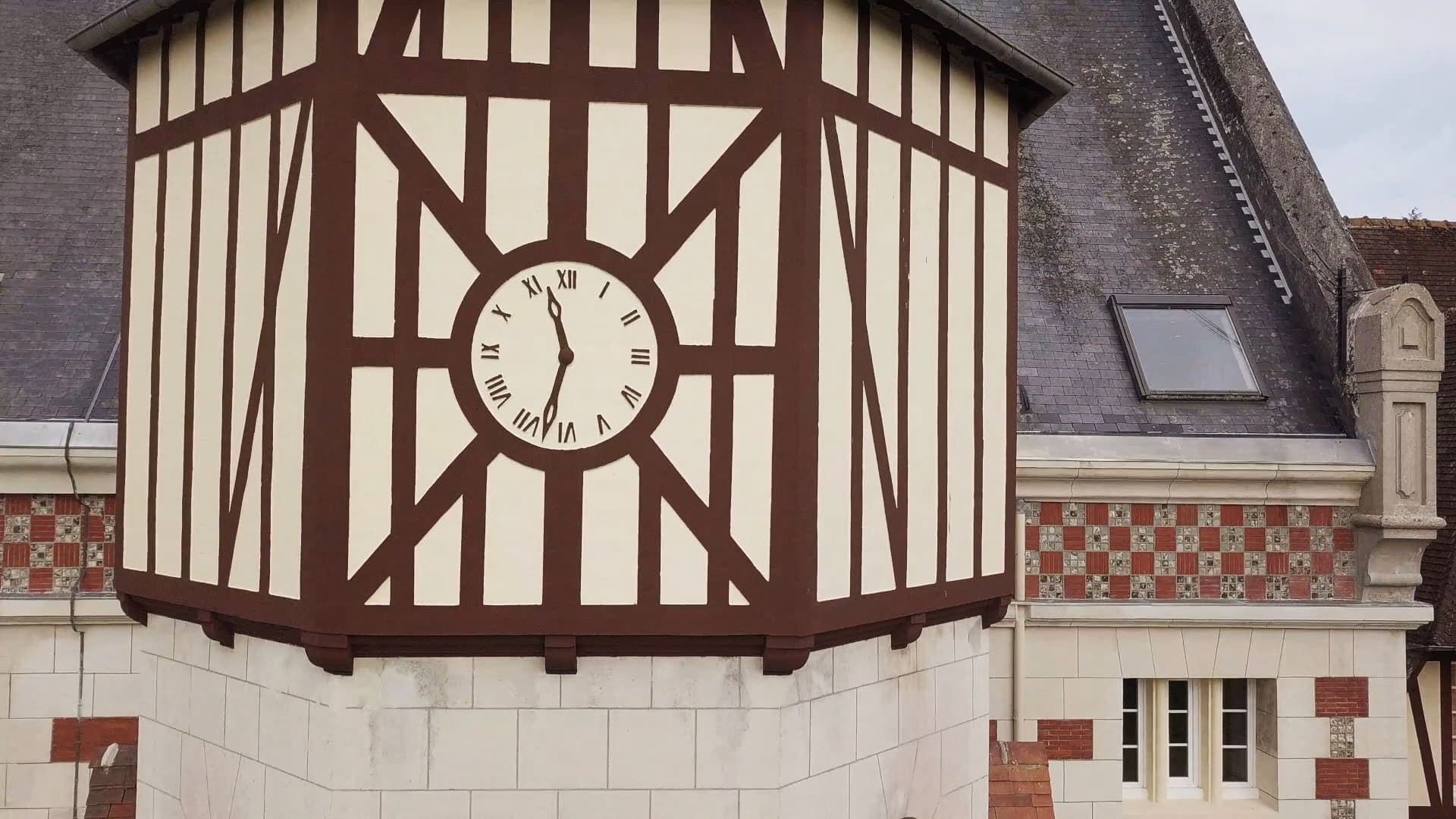 La tour à colombages de l’église et son horloge, au-dessus de la façade de pierre et de brique.